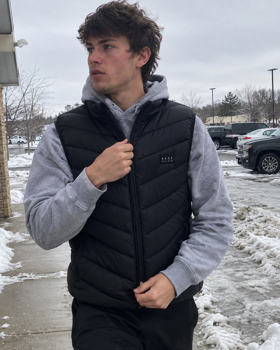 Man wearing the black NØRTHEN heated vest over a grey hoodie